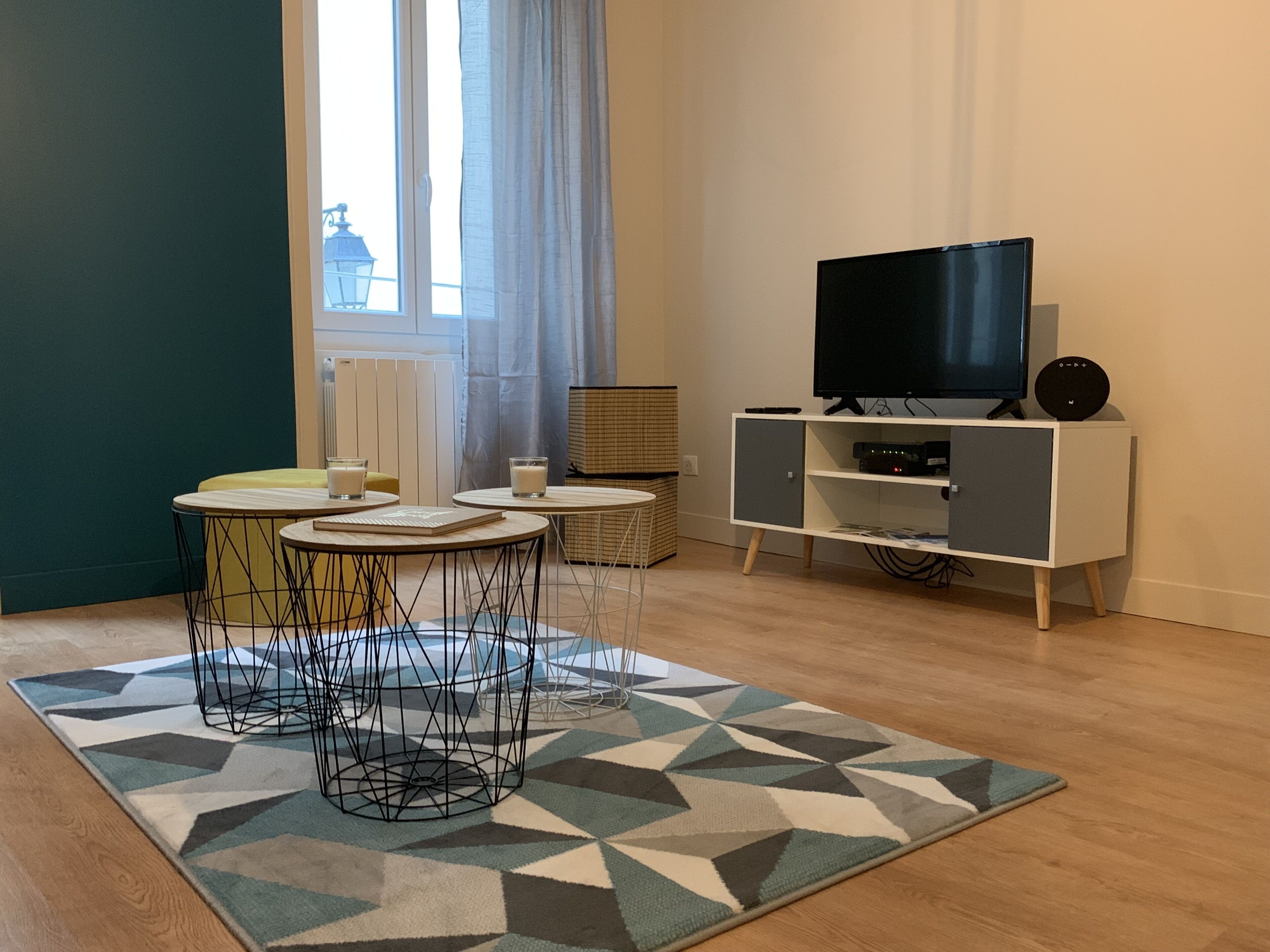 Una sala de estar moderna con un televisor, un mueble pequeño y una alfombra estampada.