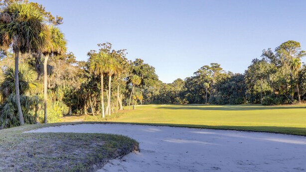 A golf course with sand bunkers, trees, and a clear sky. - Sunset Rentals | Evian 217 (Hilton Head)