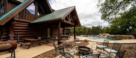 A rustic cabin with a stone patio, outdoor seating, and a swimming pool.