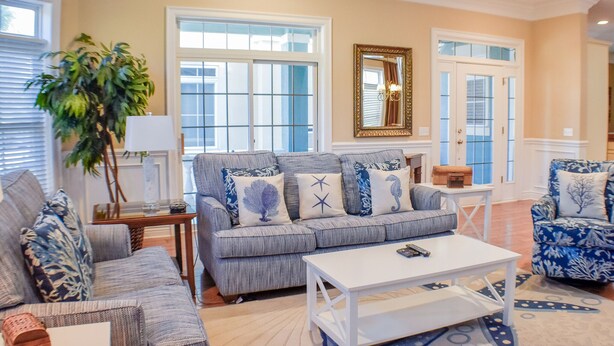 A living room with a gray sofa, blue patterned armchair, and a white coffee table. - Sunset Rentals | Crabline 39 | Dog Friendly (Hilton Head Island)