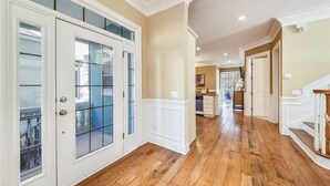 A spacious hallway with wooden flooring, white doors with glass panels, and a view into a kitchen area. - Sunset Rentals | Crabline 39 | Dog Friendly (Hilton Head Island)