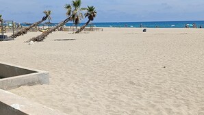 A beach with palm trees, umbrellas, and a clear sky. - 4-STAR VILLA TORREILLES SEASIDE RESORT (TORREILLES)