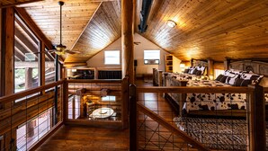 A spacious loft bedroom with a large bed, a wooden ceiling, and a view of the outdoors. - Perfect for Families! Big Patio, Pool/Hot Tub (Burnet)