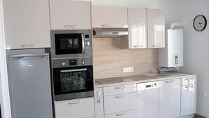 Una cocina moderna con electrodomésticos de acero inoxidable, horno empotrado, microondas y lavavajillas.