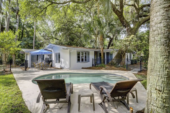 A house with a swimming pool, outdoor seating, and a covered patio.