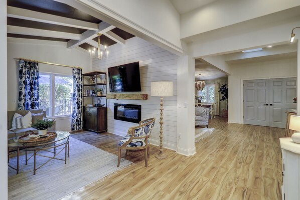 A spacious living room with a fireplace, a television, and a dining area with a glass table.
