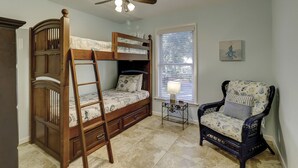 A room with a bunk bed, a ladder, a chair, a small table with a lamp, and a ceiling fan. - Sunset Rentals | Bradley Circle 9 | Dog Friendly (Hilton Head Island)