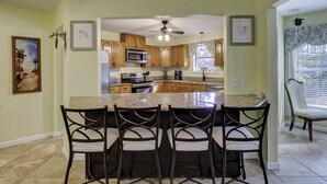A kitchen with a central island, wooden cabinets, a microwave, and a ceiling fan. - Sunset Rentals | Bradley Circle 9 | Dog Friendly (Hilton Head Island)