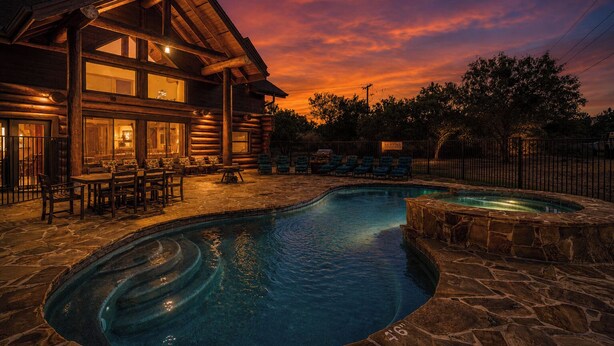 A log cabin with a pool and outdoor seating.