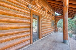 A log cabin with a covered porch and a door leading to the interior.