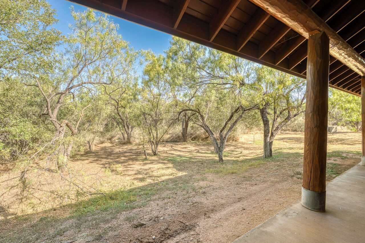 A covered outdoor area with a dirt path and trees.
