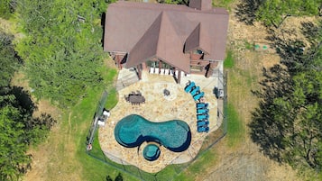 An aerial view of a house with a swimming pool, patio furniture, and a fenced yard.