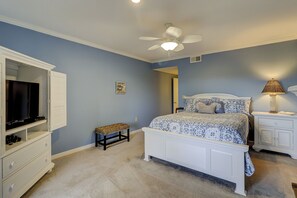 A bedroom with a bed, a TV, a ceiling fan, a lamp, and a small stool. - Sunset Rentals | Captains Walk 458 (Hilton Head Island)