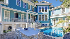 A two-story house with a pool, outdoor seating, and a staircase leading to a balcony. - Sunset Rentals | Egret 5 (Hilton Head Island)