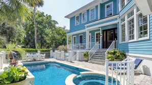 A two-story house with a swimming pool, surrounded by lush greenery and a white fence. - Sunset Rentals | Egret 5 (Hilton Head Island)