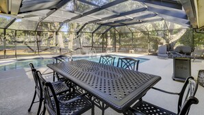An outdoor pool area with a covered patio, metal table and chairs, and a grill. - Sunset Rentals | Baynard Park 6 | Dog Friendly (Hilton Head Island)