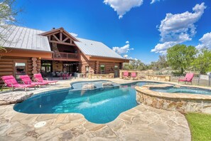 A log cabin with a swimming pool, outdoor seating, and a stone deck.