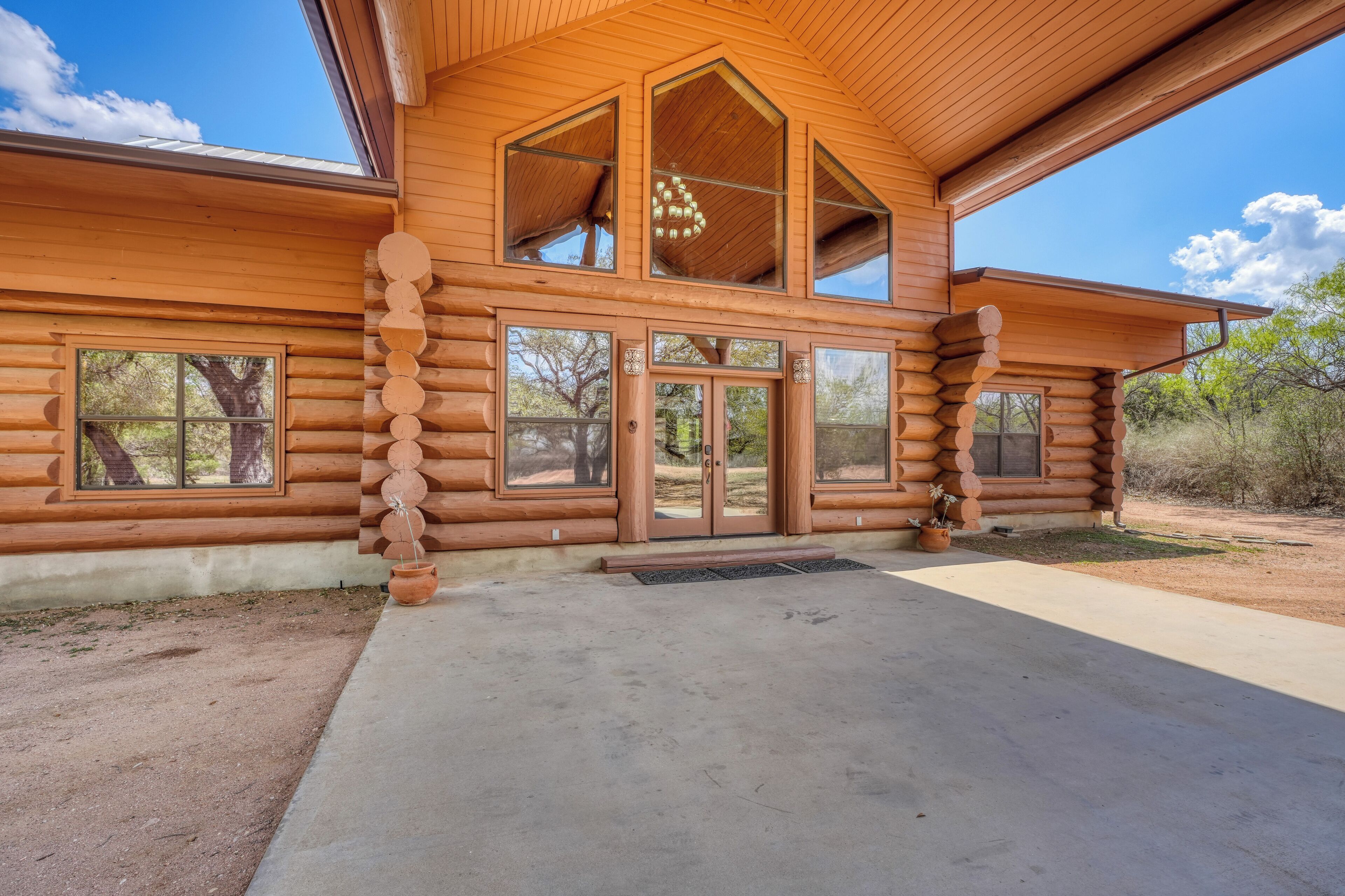 A log cabin with a large front door, multiple windows, and a covered porch.
