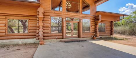 A log cabin with a large front door, multiple windows, and a covered porch.