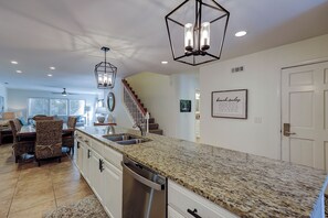 A spacious kitchen with granite countertops, stainless steel appliances, and a modern pendant light fixture. - Sunset Rentals | Tennismaster 904 (Hilton Head)