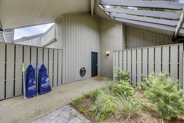 A covered outdoor area with a concrete floor, a door, and a small garden with various plants. - Sunset Rentals | Tennismaster 904 (Hilton Head)