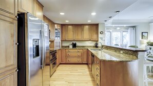Une cuisine dotée de meubles en bois, d’appareils électroménagers en acier inoxydable et d’un plan de travail en granit.