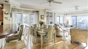 Un grand espace de vie comprenant une table à manger, des chaises, un canapé et un ventilateur de plafond.