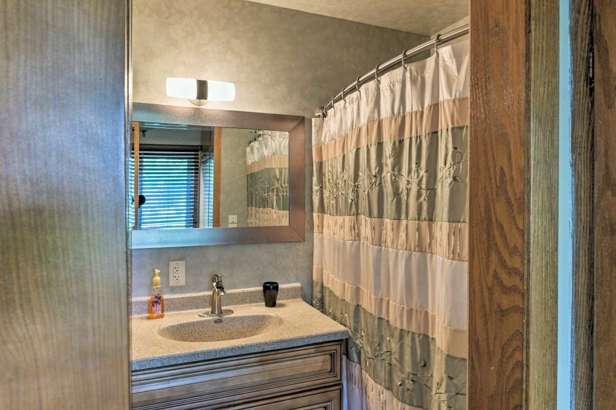 Een badkamer met een wastafel, spiegel en douchegordijn.