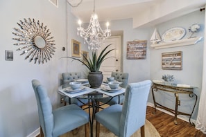 A dining area with a chandelier, a sunburst mirror, and a nautical-themed wall decor.