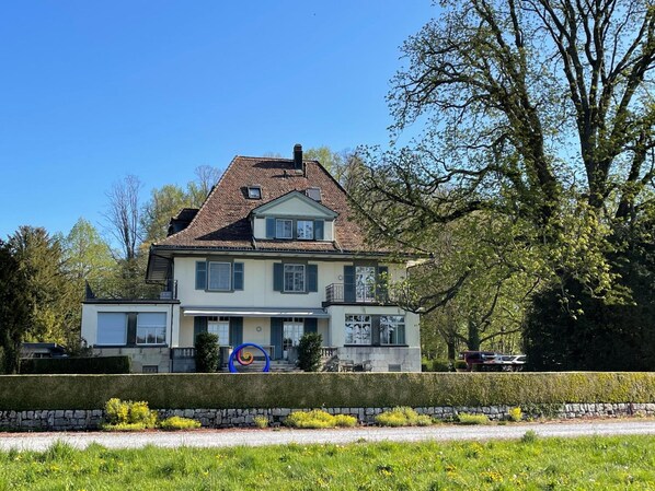 A two-story house with a symmetrical facade, a central entrance, and a visible garden area in front.