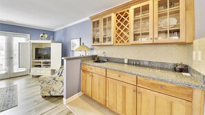 A kitchen with wooden cabinets, a granite countertop, and a built-in TV. - Sunset Rentals | Evian 164 (Hilton Head)