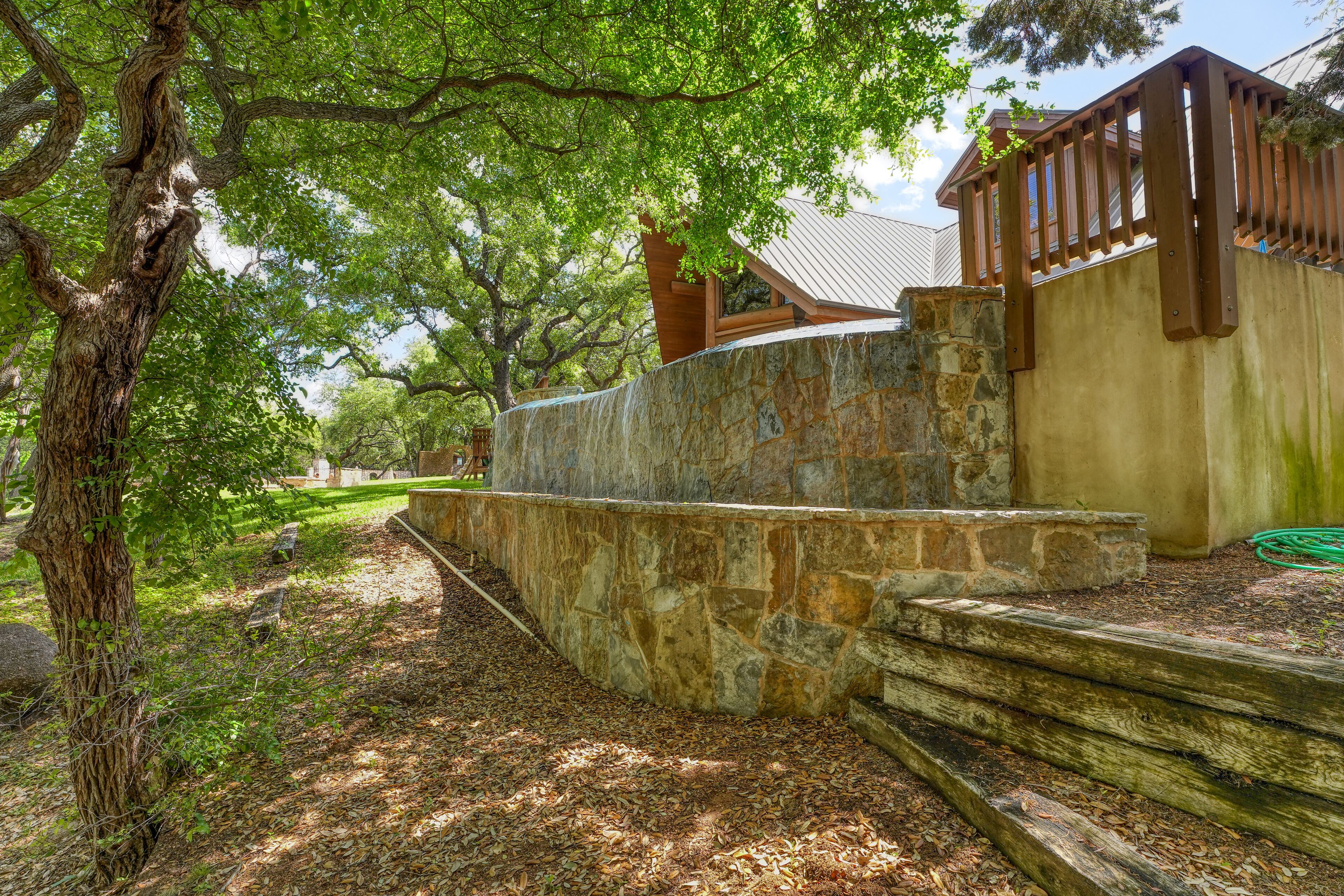 Un muro de piedra con una escalera de madera que conduce a un edificio con techo inclinado.
