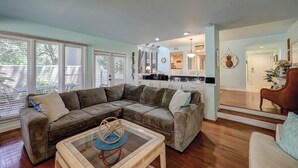 A living room with a sectional sofa, a glass coffee table, and a kitchen in the background. - Sunset Rentals | St. Andrews 1772 | Dog Friendly (Hilton Head)