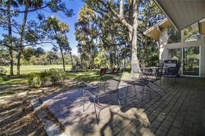 A patio area with outdoor furniture, a grill, and a view of a golf course.
