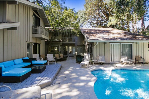 A two-story house with a swimming pool, outdoor seating, and a covered patio.