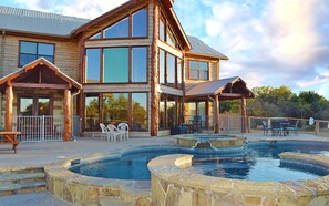 Une grande maison en bois avec une piscine et un espace salon extérieur.