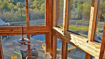Una habitación amplia con ventanas grandes, ventilador de techo y vistas al exterior.