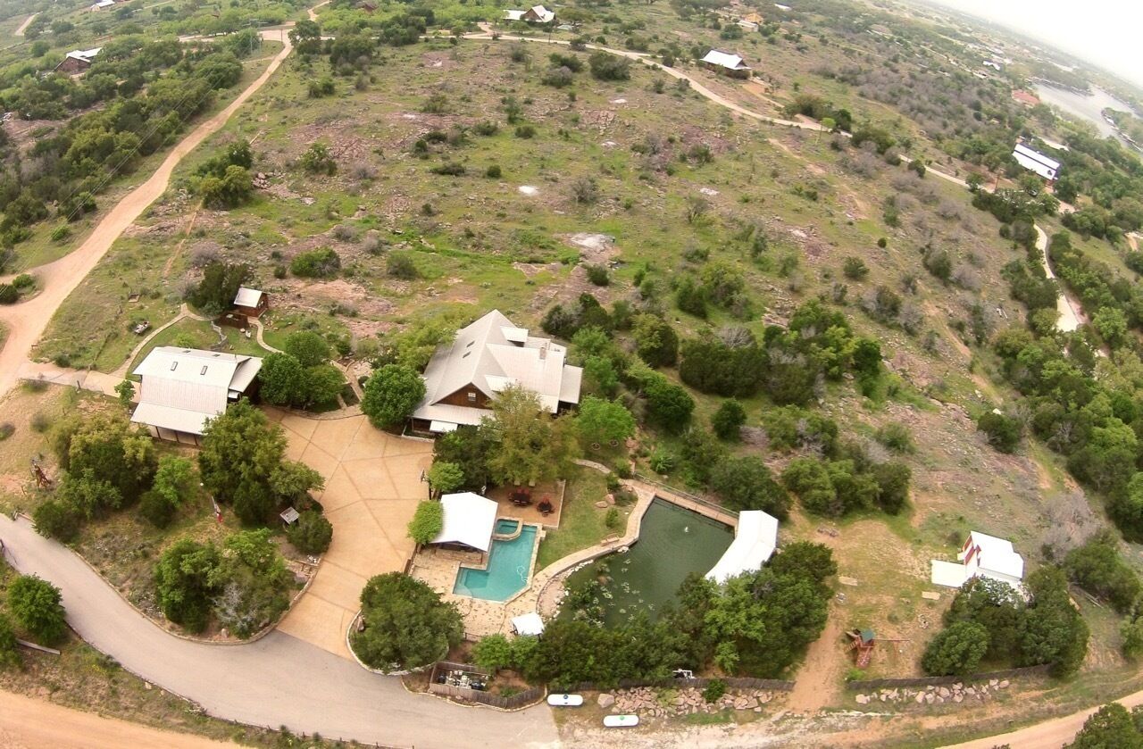 Vista aérea de una zona residencial con varias casas, una piscina y un gran campo verde.