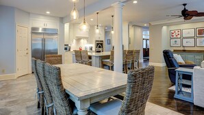 A spacious kitchen with modern appliances, a dining area with wicker chairs, and a ceiling fan. - Sunset Rentals | Mooring Buoy 179 (Hilton Head Island)