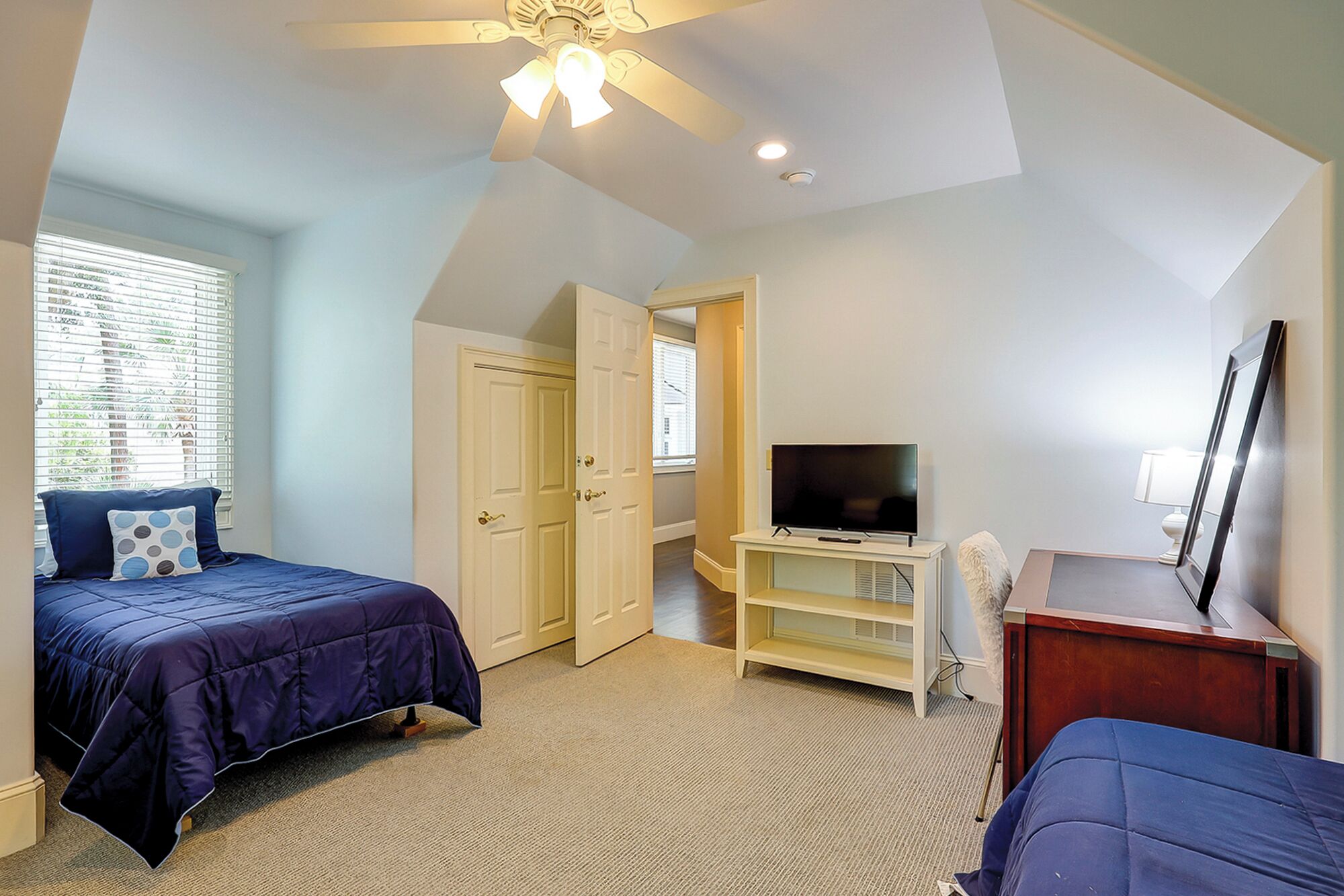 Une chambre avec deux lits, une télévision et un ventilateur de plafond.