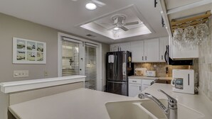 A modern kitchen with a built-in oven, a refrigerator, a coffee maker, and a sink with a faucet. - Sunset Rentals | St. Andrews 1876 | Dog Friendly (Hilton Head Island)