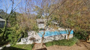 A residential area with a swimming pool, surrounded by trees and a house. - Sunset Rentals | St. Andrews 1876 | Dog Friendly (Hilton Head Island)