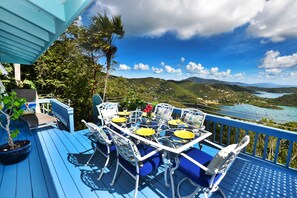 A blue deck with outdoor furniture, a potted plant, and a view of a lake with boats. - Beautiful Cottage w/Stunning View, Tesla Backup Power, Hot Tub, Family or Couple (St. John)