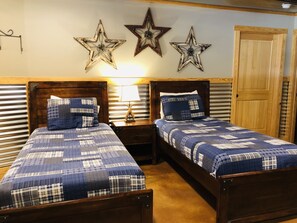 A bedroom with two beds, a nightstand with a lamp, and decorative stars on the wall. - Waterfront Retreat w/ Pool, Hot Tub & Game Room (Burnet)