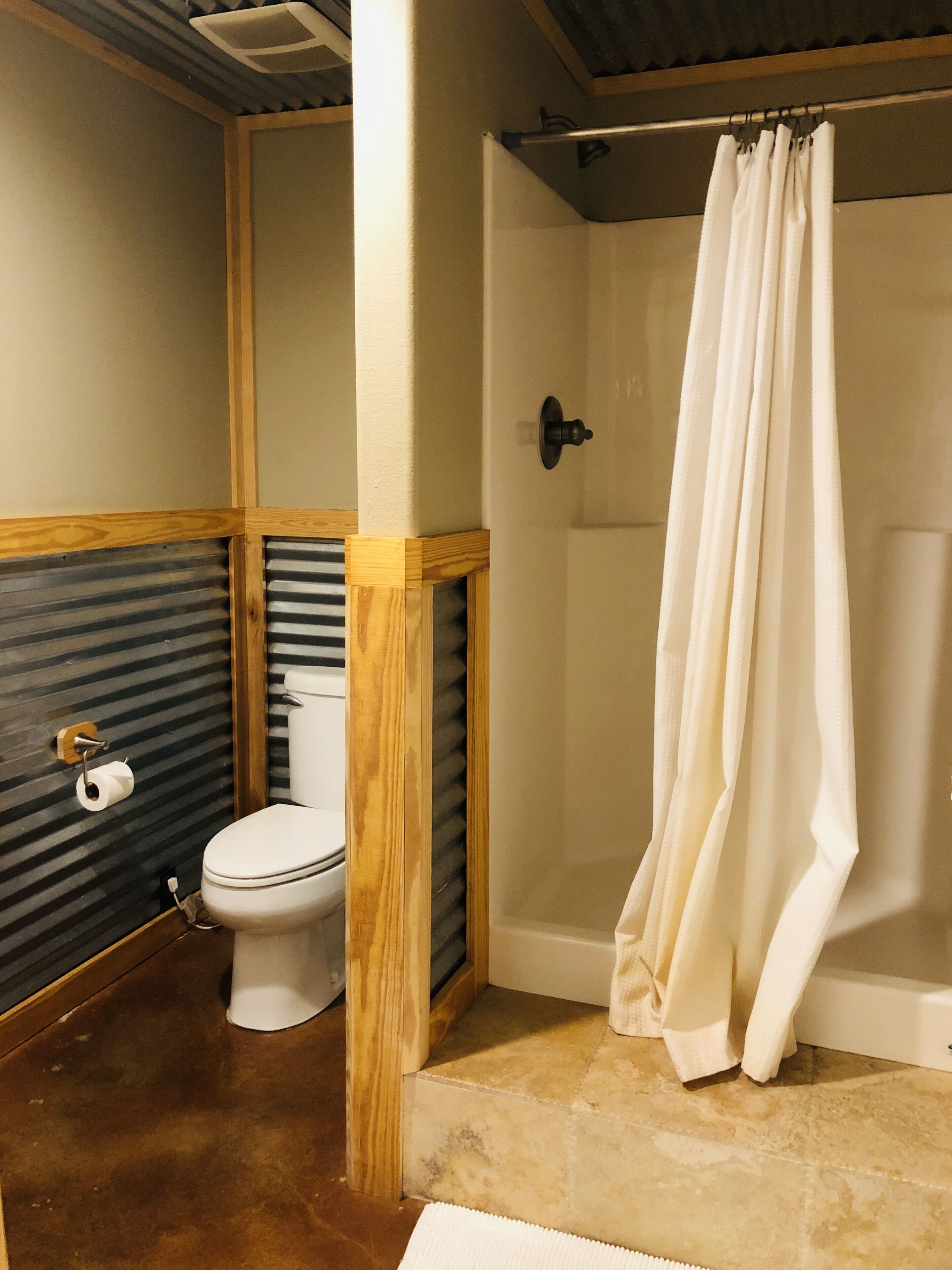 Un baño con inodoro, ducha y toallero.