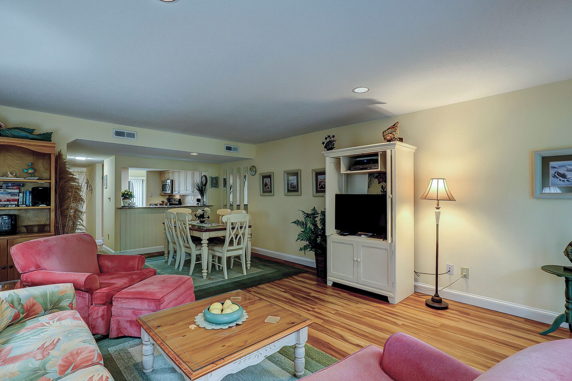 A living room with a sofa, a coffee table, a television, and a dining area with chairs and a table.