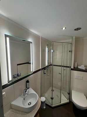 Une salle de bain moderne avec une douche à parois de verre, un lavabo blanc et des toilettes.