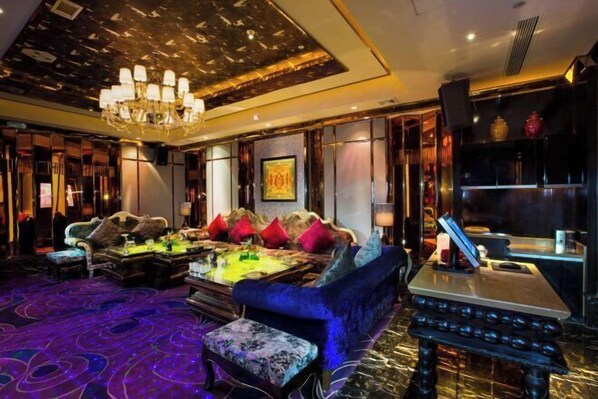 A luxurious hotel lobby with a plush blue sofa, a chandelier, and a patterned carpet. - Hopesun Hotel (Jiangyin)
