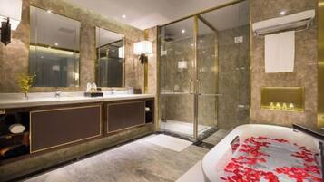A modern bathroom with a large mirror, a walk-in shower, and a bathtub with rose petals.
