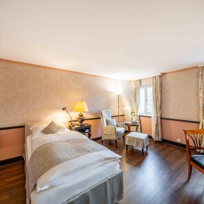 Een hotelkamer met een bed, een bureau, een stoel en een raam met gordijnen.
